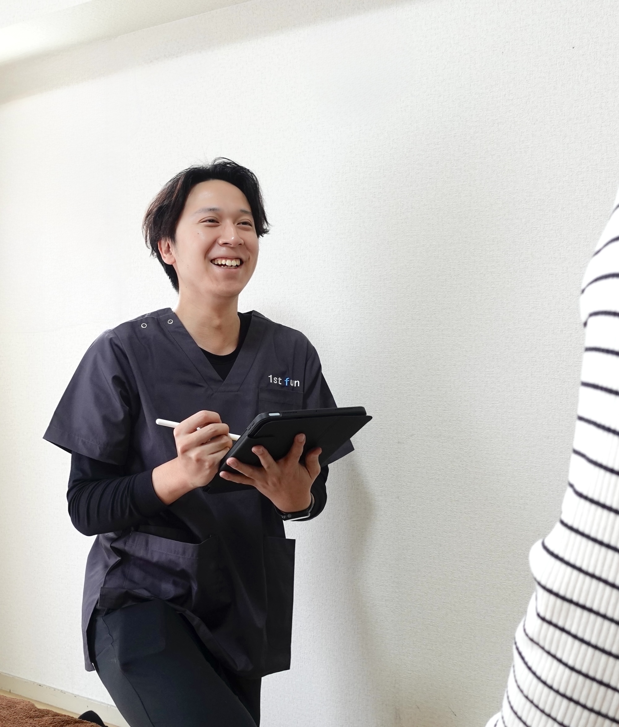 施術者が利用者と対話しながらタブレットに記録する様子