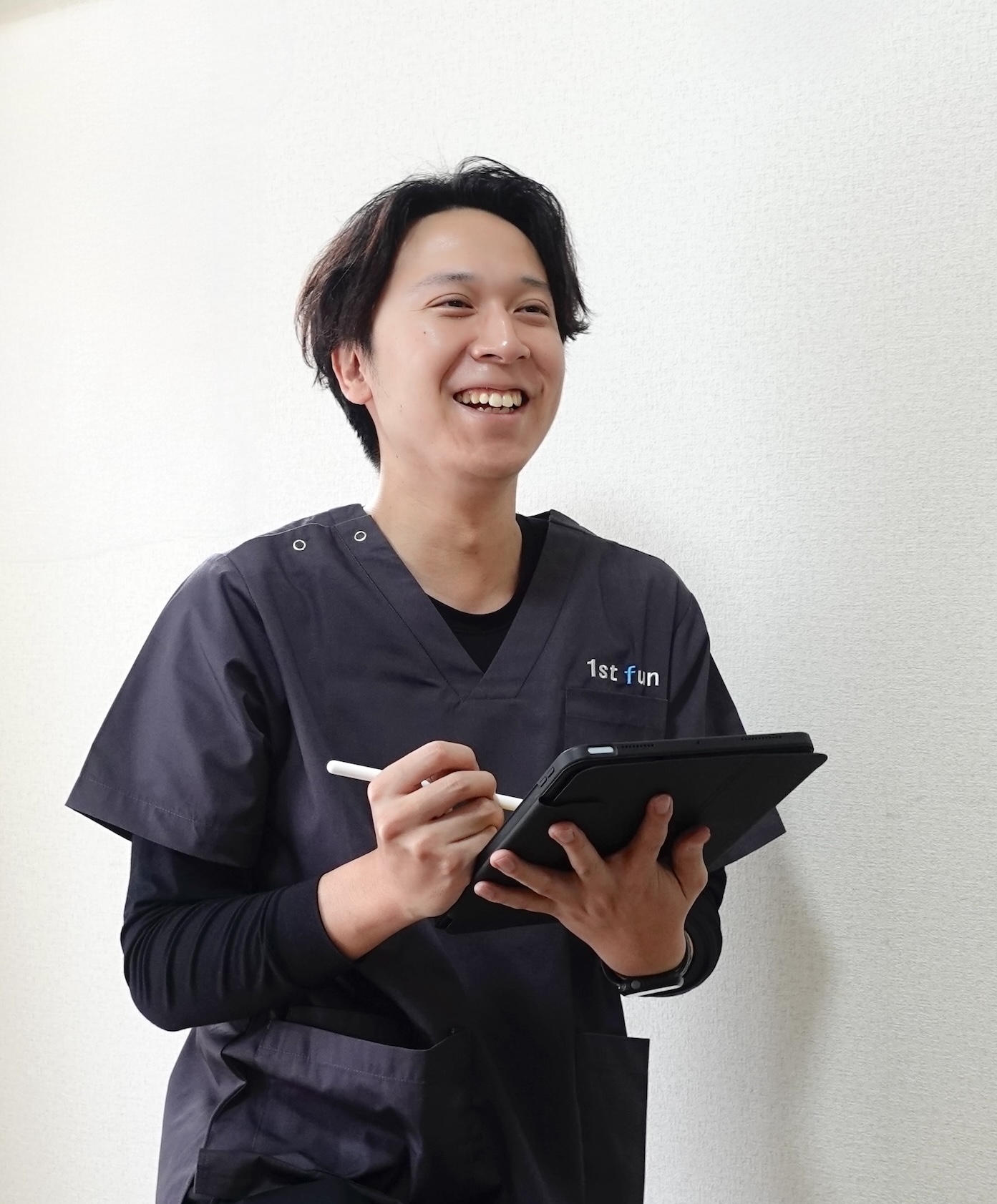 タブレットを手に利用者と対話する理学療法士の岩崎凌万